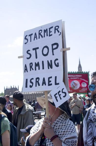 woman carrying sign 'Starmer stop arming Israel FFS'
