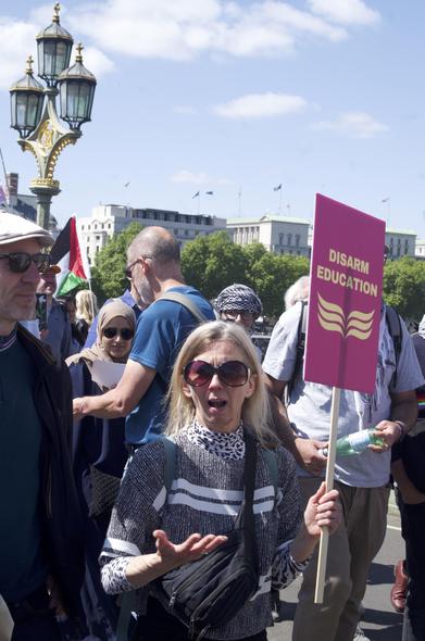 woman carrying sign 'disarm education'