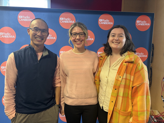 Three people standing in front of an ABC Radio Canberra backdrop