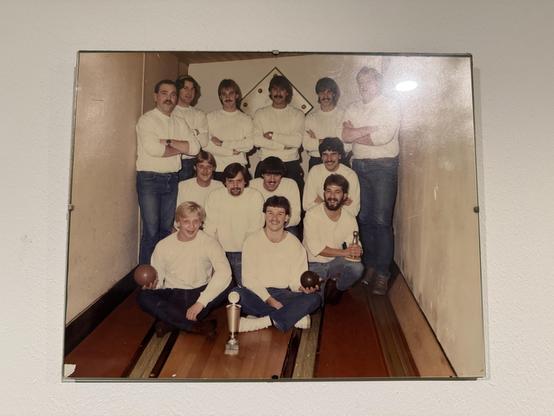 Gruppenbild einer Kegelgruppe. Alles Männer, Vokuhilas und Schnurrbärte dominieren das Bild.