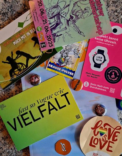 Eine bunte Sammlung an Flyern, Stickern und Buttons der Vereine, die auf dem About Pop Festival vertreten waren, liegen auf einem Haufen