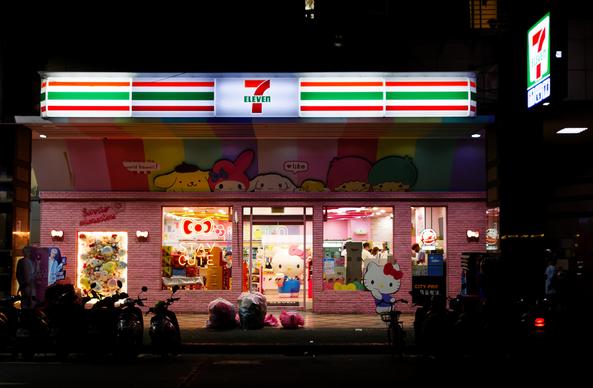 Storefront of a Hello Kitty-themed 7-Eleven at night with a “Stay Cute” neon sign in one window
