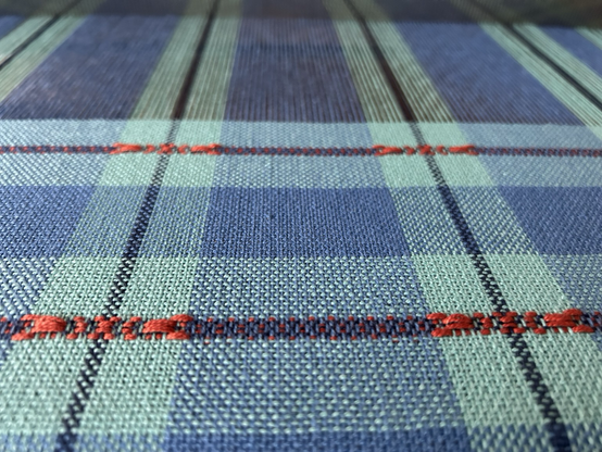 A close up look at handwoven blue striped fabric on a hand loom