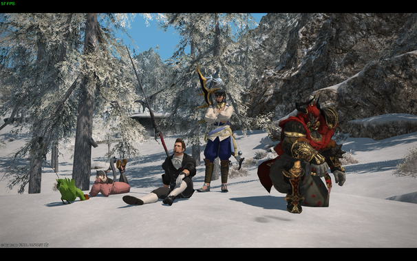 In a snowy landscape of Final Fantasy XIV, five diverse characters are at rest. Leaning against a snowy tree is a character dressed in a black and white tunic and black pants, leaning his head back and gazing up. Farther to the left, a sprawled-out Miqo'te, or cat-like girl wearing a pink blanket is sitting on her stomach. Near the Miqo'te is a green moogle. In the center stands the Warrior of Light holding a powerful bow. To the right stands a dark-skinned figure in heavy crimson and gold armor. Behind them is a forest of snow-covered trees and a large mountain.
