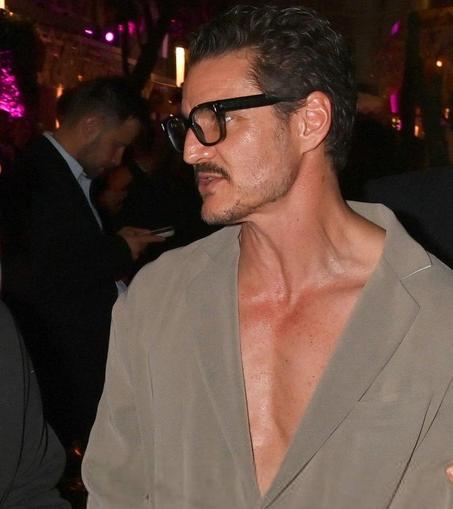Pedro Pascal in Cannes. He wears agrey jacket without a shirt, shoes and a muscle shirt so he shows off his chest and neck 
