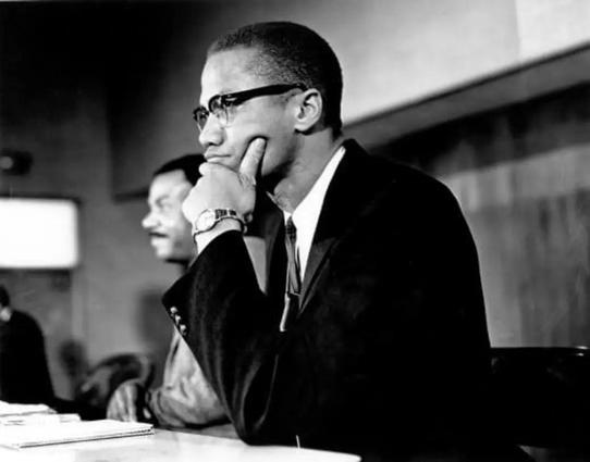 Malcolm X sitting at a desk