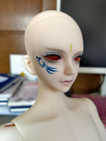 Puppe in Portrait mit blauer Tätowierung im Gesicht, stilistisches Muster. Er hat noch keine Haare und auch noch keine Augen. Nahaufnahme bei Tageslicht