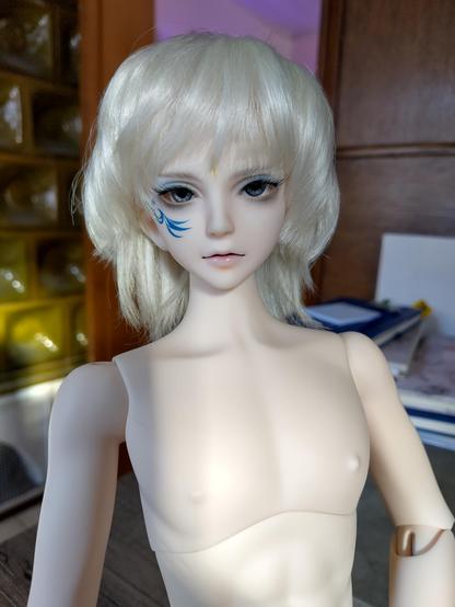 Puppe mit graublauen Augen, platinblonden kurzen Haaren, blauem Tattoo im Gesicht