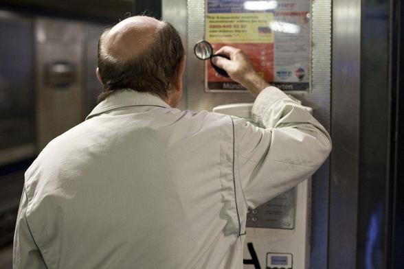 middle-aged friendly: photograph of a balding man trying to read a notice using a magnifying glass. Photo attribution: Flickr user philippeleroyer