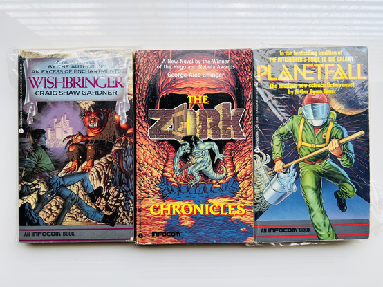 3 paper books based on Infocom games. From left-to-right, Wishbringer, The Zork Chronicles and Planetfall. Each of these were originally text adventure games. Years later Infocom decided to actually create paperback novels of some of their hits. (I wish they'd paid someone to write Lurking Horror, or Douglas Adams to write Bureaucracy in book form!) 