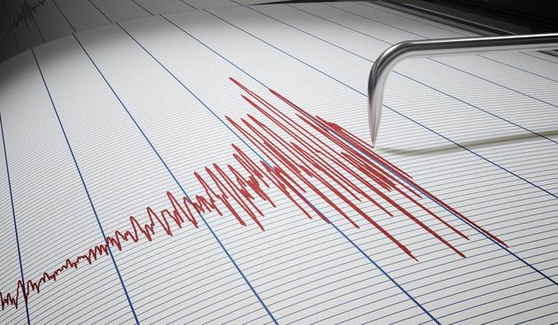 A needle of a seismograph drawing a growing amplitude with red ink on paper. Photo: Adobe Stock