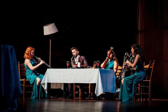 Je ziet een tafel op een podium met muzikanten eromheen.