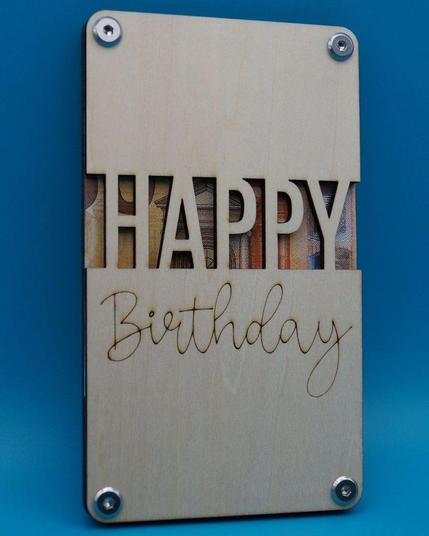 Fertig montiertes Holz-Geldgeschenk mit ausgelasertem „HAPPY“-Schriftzug und graviertem „Birthday“, hinterlegt mit Geldscheinen.