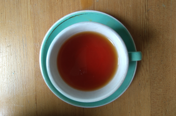A cup of red bush tea in a white cup on a green saucer sitting on a wooden table.

Nicolas Mouart, all rights reserved.