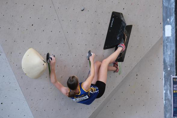 Photo of a climber on an overhung boulder problem.