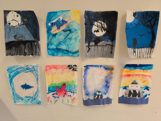 Eight paintings by kids. Three are darker tones, with the moon in the background. The others are very colorful with ocean creatures.