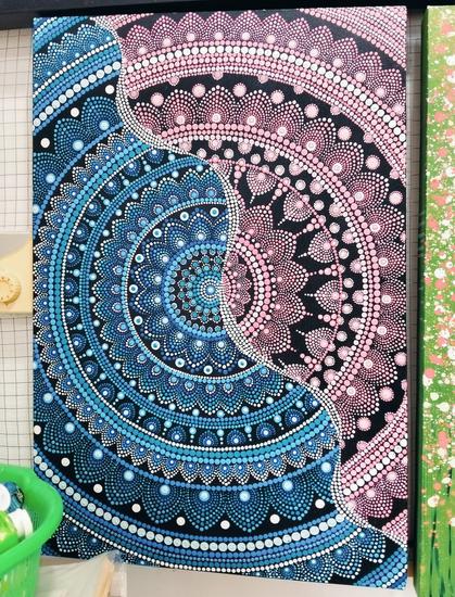 a mandala design, cropped at the sides, a wavy white line of dots running diagonally, half he mandala is blue, half pink
