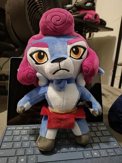A picture of a plushy of the character Absa from Rivals of Aether sitting on the keyboard of a Microsoft Surface Pro 11, it is several inches  taller than the device is long.