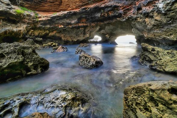 London Bridge in Portsea, Melbourne, is a remarkable coastal rock formation shaped by the region’s unique geology and natural history. Formed primarily from limestone, this natural archway emerged through thousands of years of erosion caused by relentless wave action and weathering along the Bass Strait coastline. The limestone itself dates back to the Miocene epoch, approximately 10 to 15 million years ago, originating from the accumulation of marine sediments. Over time, the sea carved caves and arches into the cliffs, creating the iconic structure known as London Bridge. The surrounding area supports diverse coastal vegetation adapted to the salty, windy environment, while nearby marine ecosystems thrive with a variety of fish, seabirds, and intertidal life, making London Bridge not only a geological wonder but also an important habitat in Victoria’s natural history.