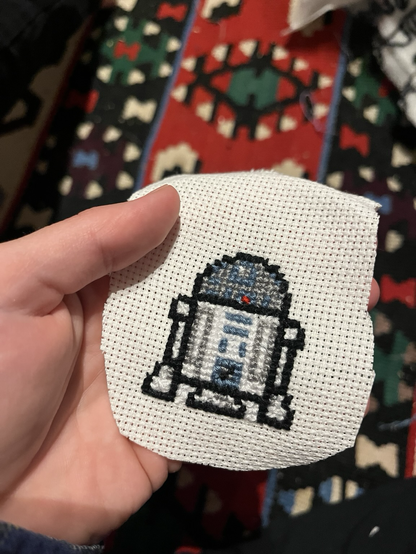  small R2D2 cross stitched on piece of material 