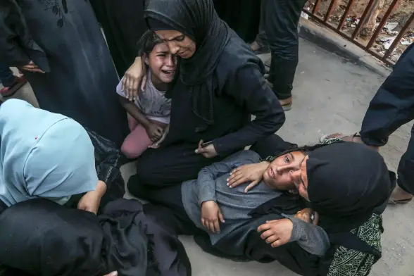 A girl laying in the lap of her mother looks like she's about to pass out from hunger during a funeral.