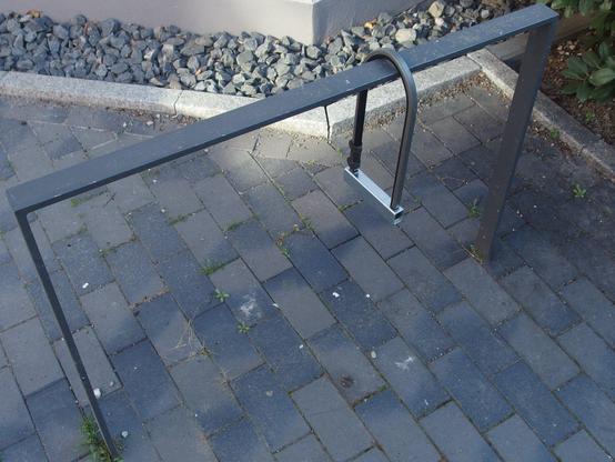 A lonesome locked u-lock (aka LuftSchloss) hanging from a rectangular metal bike rack.
