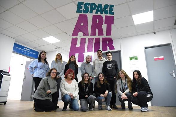 Photo de groupe prise dans un couloir de l’Espace Arthur à l’Hôpital Salvator. Treize professionnel·le·s posent souriants face à l’objectif, debout et accroupis sous un lettrage mural coloré indiquant "ESPACE ARTHUR". Au fond, des panneaux signalétiques orientent vers les consultations de pédopsychiatrie.