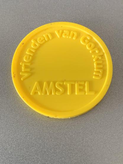 Een geel plastic consumptiemuntje waarop staat "Vrienden van Gorkum" en AMSTEL.