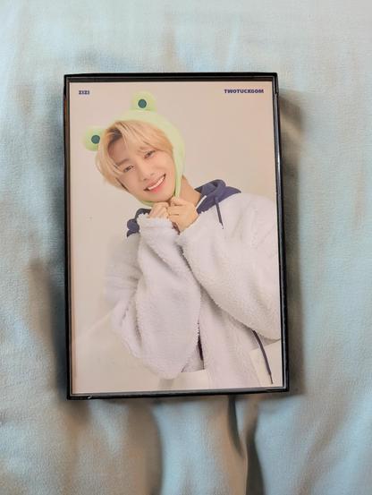 Image shows a framed picture of Hyungwon wearing a frog hat.