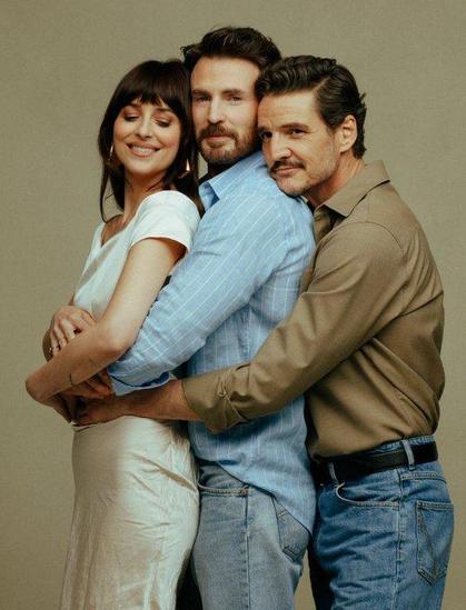Dakota Johnson gets hugged of Chris Evans from behind and Pedro Pascal hugs Chris Evans from behind. It's a threefold hug.
