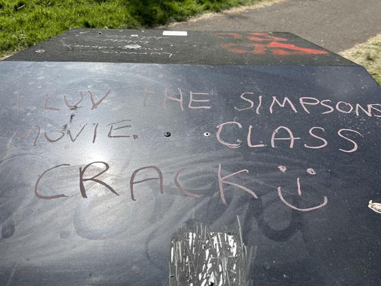 Graffiti on a bin which says “I luv the Simpsons movie class crack :-)”