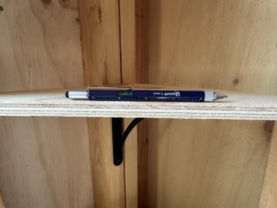 Multi-tool pen being used to level a shelf in a shed