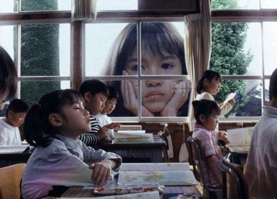 Fotograma de Taste of tea donde se ve una clase con niños, una niña con cometas en primer plano y la cara de esa misma niña gigante en los ventanales