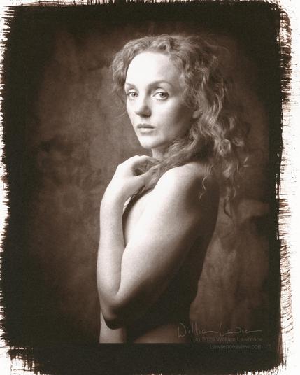 Model Ivory Flame poses nude with body in profile and head turned so eyes engage the viewer.  Her arm covers her breast, and holds some of her long hair.  This is a gold-toned kallitype, so monochrome with a slight red/purple tone to the photo.