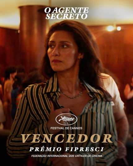 Cartaz de anuncio do premio  descrito no post,  na imagem a cena do filme com uma atriz (Maria Fernanda Candido)  de cabelos longos , camisa de botões listrada  de marrom e preto num ambiente com varias pessoas  dispersas atrás, o simbolo da premiaçao de Cannes , escrito  em letra grande VENCEDOR  