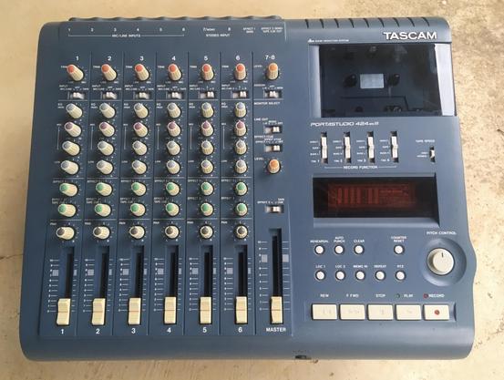 A top-down view of a blue Tascam 424mkIII multitrack cassette recorder, sitting on a blank, off-white surface.