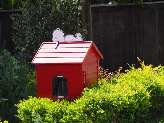 A little red house with Snoopy, the cartoon character dog, lying along the roof line.