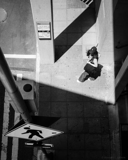 Black and white photo of a woman with a bag near a crosswalk