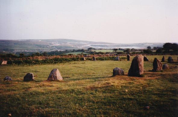 A colour photo taken in 1994 of the northern arc of the prehistoric stone circle at Brisworthy on Dartmoor. The circle, restored in 1909, is about 25m across and has 24 stones remaining out of the original approx 42. The edge of Dartmoor can be seen in the distance.