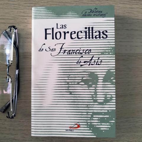 Portada del libro Las Florecillas de San Francisco de Asís. La portada es muy sencilla, blanca con tonalidades en verde. Se puede ver el título en la parte superior central y se insinúa un rostro.