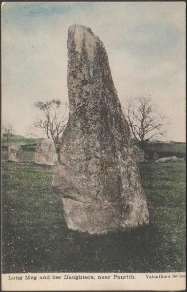 A vintage postcard showing Long Meg, a 3.6m or almost 12ft tall standing stone or menhir which lies just outside a large stone circle at Little Salkeld in Cumberland, now Cumbria. Some of the stones of the circle can be seen behind. On the other side of Long Meg are petroglyphs: a cup and ring mark, a spiral, and an incomplete concentric circle. The circle is an oval, about 100m x 93m, and has 59 of the original 70 or so stones remaining.