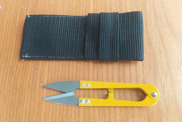 A small set of yellow thread snips below a small black webbing case
 