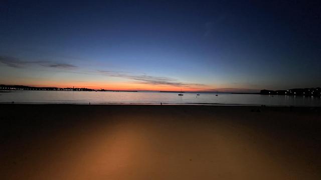 Le soleil s’est couché sur la baie de Saint-Jean-de-Luz. Le sable au premier plan est éclairé d’or, l’océan est calme et luit d’un reflet d’argent, quelques rares petites embarcations se détachent en contre jour. Le ciel s’amorce d’un orange flamboyant en dégradé par un jaune timide vers un bleu ébène. 