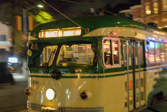 A close-up night photo of the F Market streetcar with motion blur, captured at high ISO 