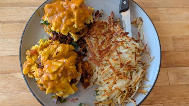Plate of plantain biscuits and gravy with scrambled eggs and hash browns from Plenty of Huevos in Lincolnshire, Illinois, USA.