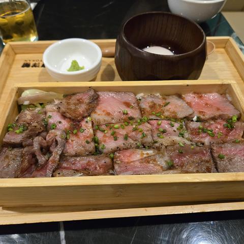 A box of A5 wagyu on rice with some chopped scallions on top