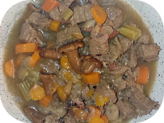 Gros plan sur une assiette. On distingue les morceaux de viande, les champignons, le céleri, les carottes...