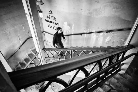 Black and white photo of a man walking up stairs.