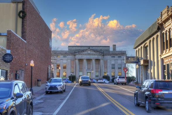 Carroll County Courthouse at Sunset 

A historic Carroll County courthouse with large columns is the focal point on a street lined with parked cars under a vibrant sky 