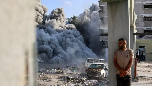 Gaza, le 1er septembre 2024. Un homme s’abrite derrière une colonne alors qu’une explosion propage de la fumée et de la poussière lors d’une frappe israélienne qui aurait visé une école dans le district de Zeitoun, à la périphérie de la ville de Gaza.